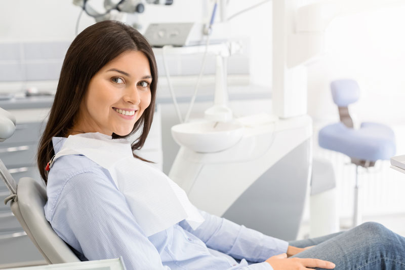 brunette-female-patient-sitting-on-dentist-chair-and-smiling